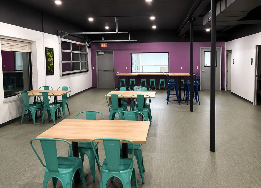 Indoor gathering space at Fetch, Play + Sip featuring casual seating, high-top tables, colorful accents, and flexible areas designed for guests and their dogs to socialize.