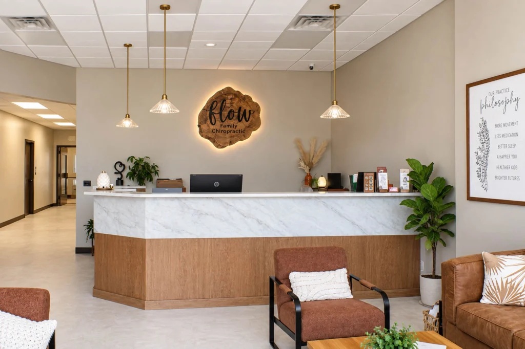 Waiting area at Flow Family Chiropractic in Kaukauna featuring comfortable seating, warm wood accents, neutral finishes, decorative lighting, and a family-friendly play area.