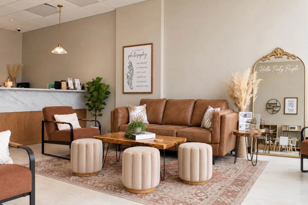 Family-friendly waiting area at Flow Family Chiropractic featuring lounge seating, a children's play space, refreshment station, and warm modern finishes.
