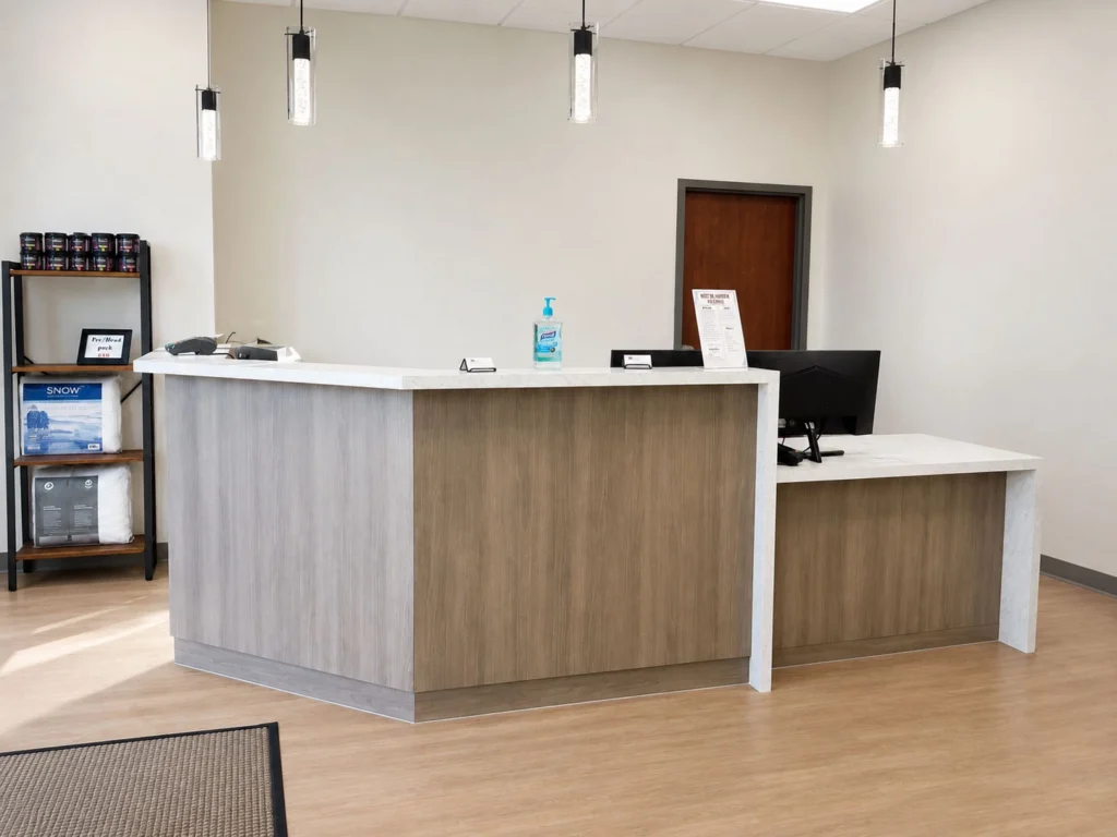 Reception area at Fox Crossing Chiropractic featuring a modern check-in desk, wood-look finishes, pendant lighting, and a welcoming patient-focused design.