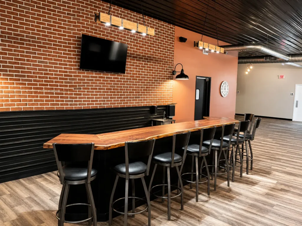 Custom bar area at Gathering Hub featuring a live-edge wood countertop, brick accent wall, mounted television, and event seating designed for social gatherings and private celebrations.