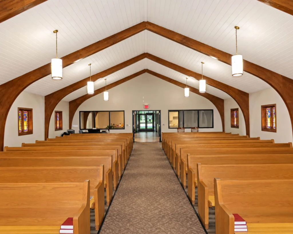 Renovated gathering area at St. Paul’s Lutheran Church featuring high-top tables, wood flooring, exposed wood beams, and open access to the expanded sanctuary.