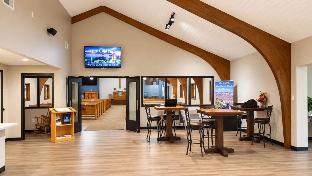 Sanctuary at St. Paul’s Lutheran Church featuring wooden pews, a central aisle, vaulted ceiling with exposed wood beams, stained-glass windows, and a large wooden cross above the altar.